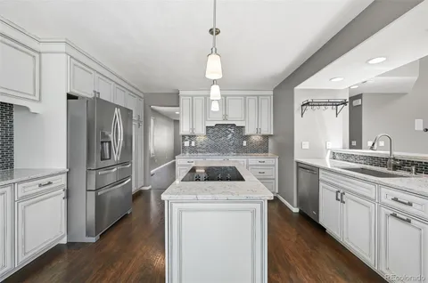 a kitchen with a refrigerator a sink and wooden floor