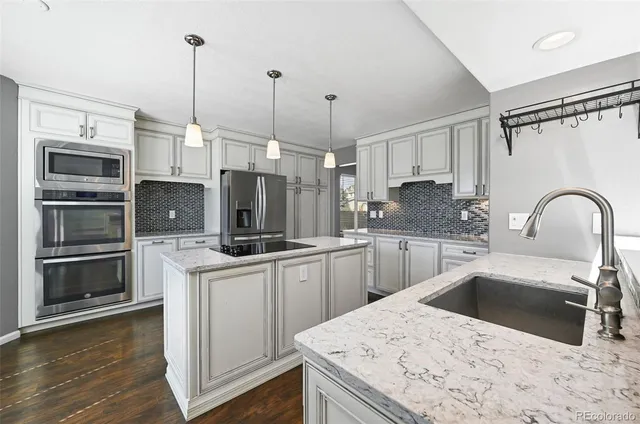 a kitchen with stainless steel appliances kitchen island granite countertop a sink a stove a microwave a counter space and cabinets