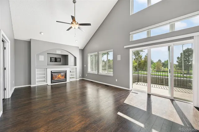 a view of a livingroom with wooden floor a ceiling fan and windows