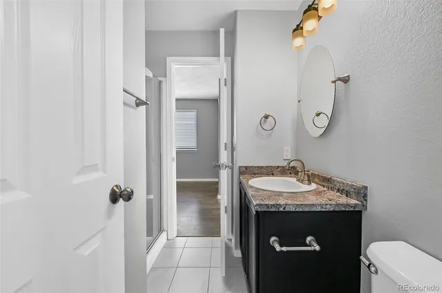 a bathroom with a granite countertop sink a toilet and shower