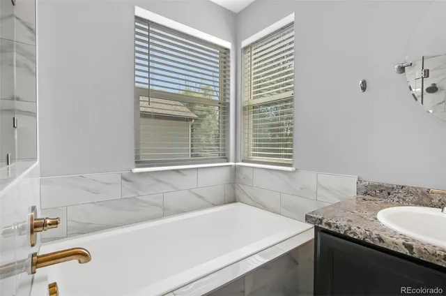 a bathroom with a granite countertop sink and a bathtub