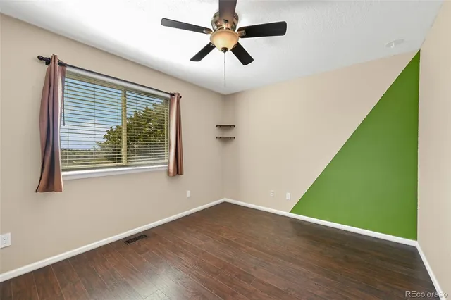 an empty room with wooden floor fan and windows