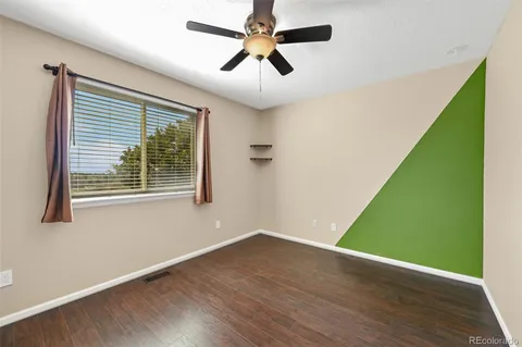an empty room with wooden floor fan and windows