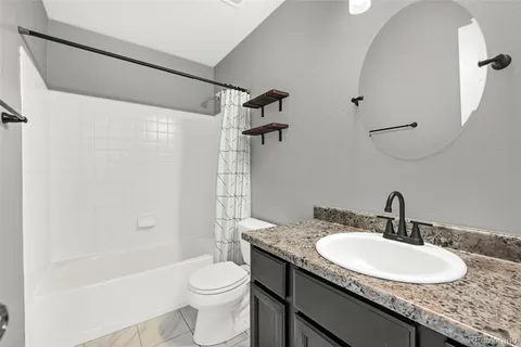 a bathroom with a granite countertop sink toilet and shower