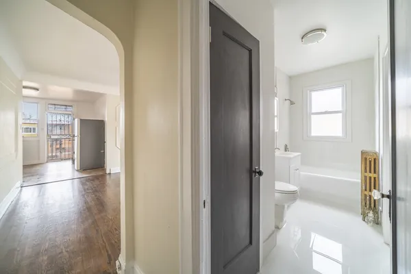 a view of a hallway with wooden floor and a bathroom