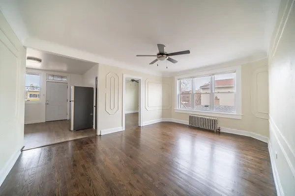a view of an empty room with a window and wooden floor