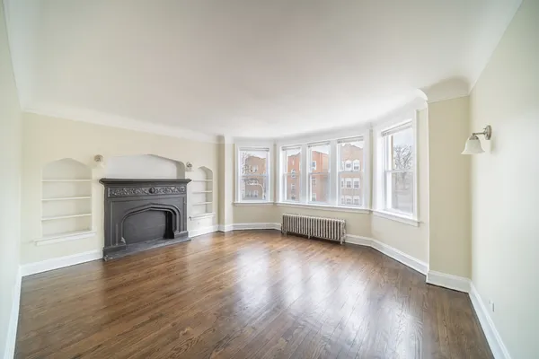 an empty room with wooden floor and fireplace