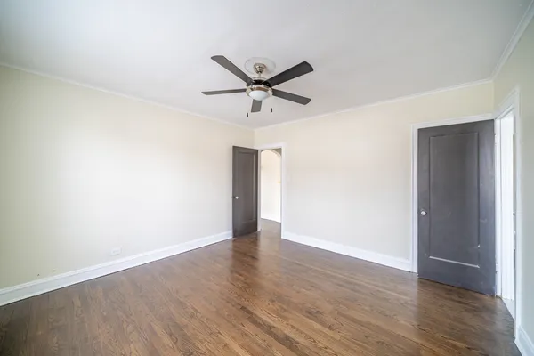 an empty room with wooden floor ceiling fan and windows