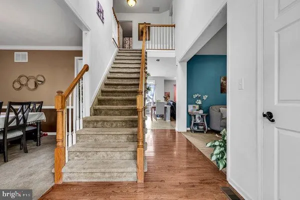a view of a hallway to a livingroom with wooden floor and stairs