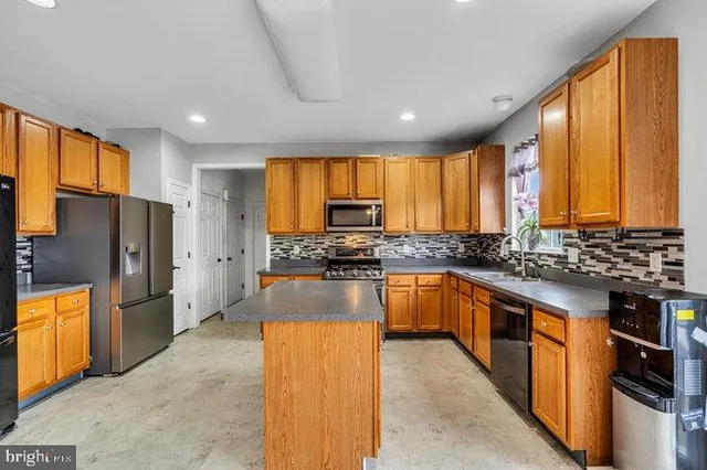 a kitchen with stainless steel appliances granite countertop a refrigerator a sink dishwasher a stove top oven with a large window and refrigerator