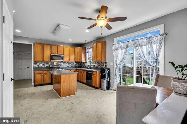 a large kitchen with stainless steel appliances granite countertop a stove a sink a refrigerator and a large window
