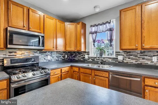 a kitchen with stainless steel appliances wooden cabinets a stove a sink and a microwave