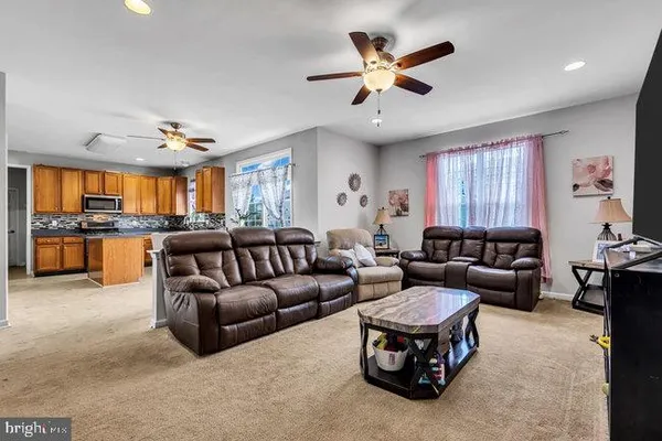 a living room with furniture kitchen view and a large window