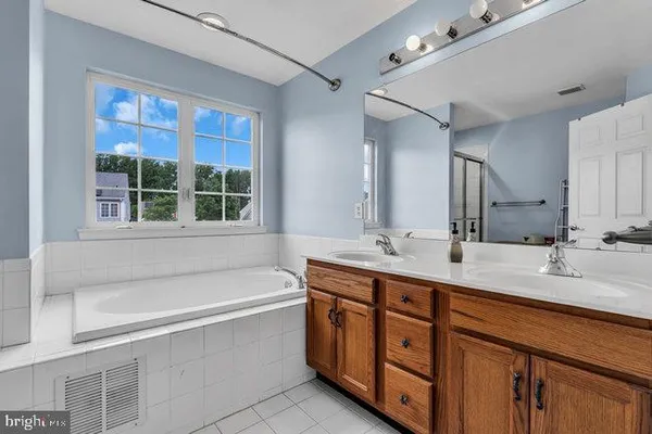 a bathroom with a tub double sink window and mirror