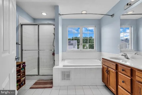 a bathroom with a granite countertop sink a mirror a bathtub and next to a window
