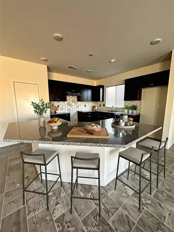 a kitchen with stainless steel appliances granite countertop a table chairs microwave and sink