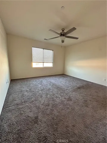 an empty room with a window and a ceiling fan