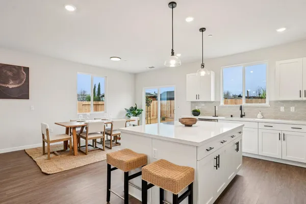 a kitchen with a dining table chairs sink and cabinets