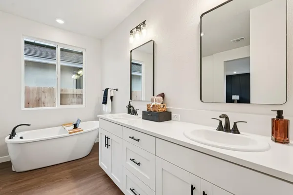 a bathroom with double vanity sinks a mirror and a bathtub