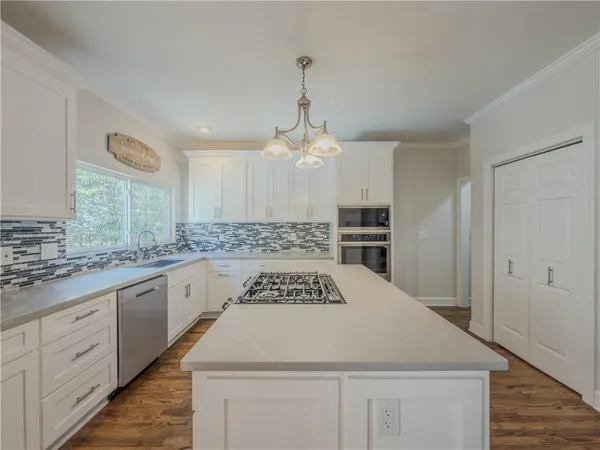 a kitchen that has a lot of white cabinets and stainless steel appliances