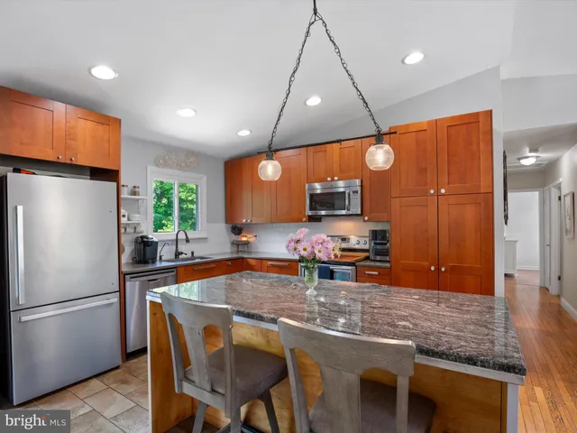 a kitchen with stainless steel appliances granite countertop a sink a stove and a wooden cabinets