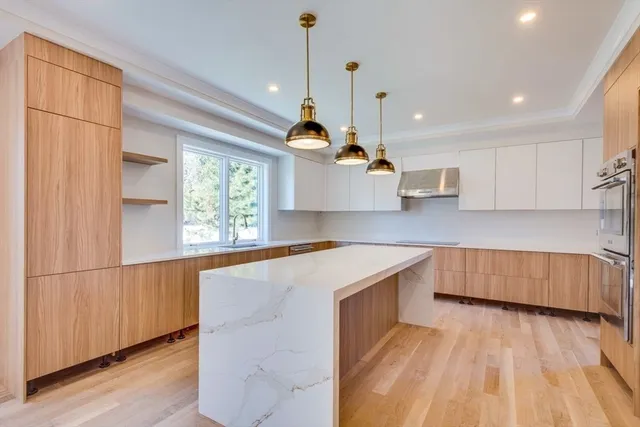 a kitchen with stainless steel appliances granite countertop a sink a microwave oven a stove and white cabinets with wooden floor