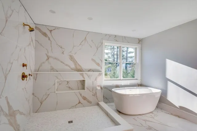 a white bath tub sitting in a bathroom next to a window