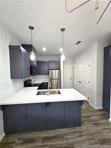 a large kitchen with kitchen island a stove a sink dishwasher and a refrigerator with wooden floor