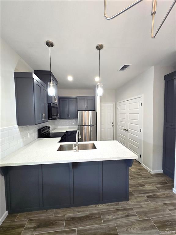 913 North Clarence Avenue, Unit 3 Edinburg, TX 78541 - Photo 3 of 11 a large kitchen with kitchen island a stove a sink dishwasher and a refrigerator with wooden floor