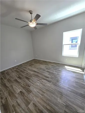 an empty room with wooden floor fan and windows