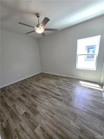 an empty room with wooden floor fan and windows
