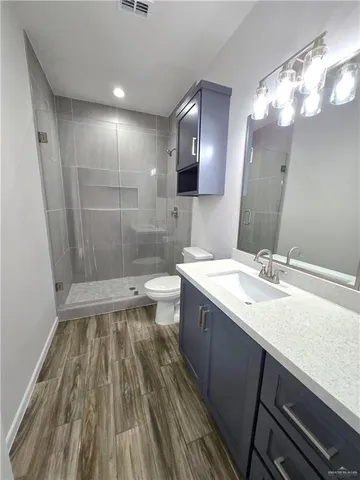 a bathroom with a sink a toilet a mirror and shower