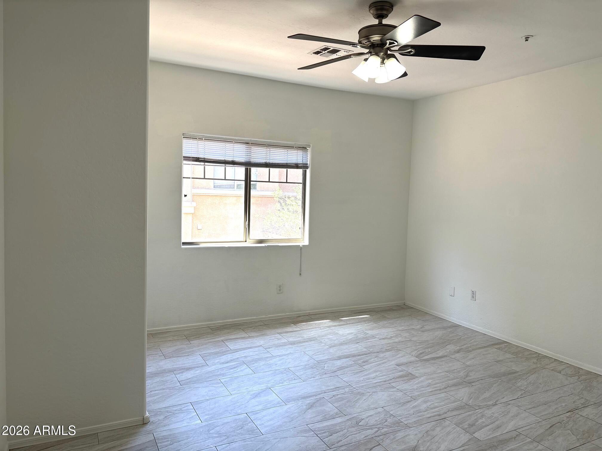 525 North Miller Road, Unit 239 Scottsdale, AZ 85257 - Photo 17 of 52 an empty room with wooden floor ceiling fan and windows