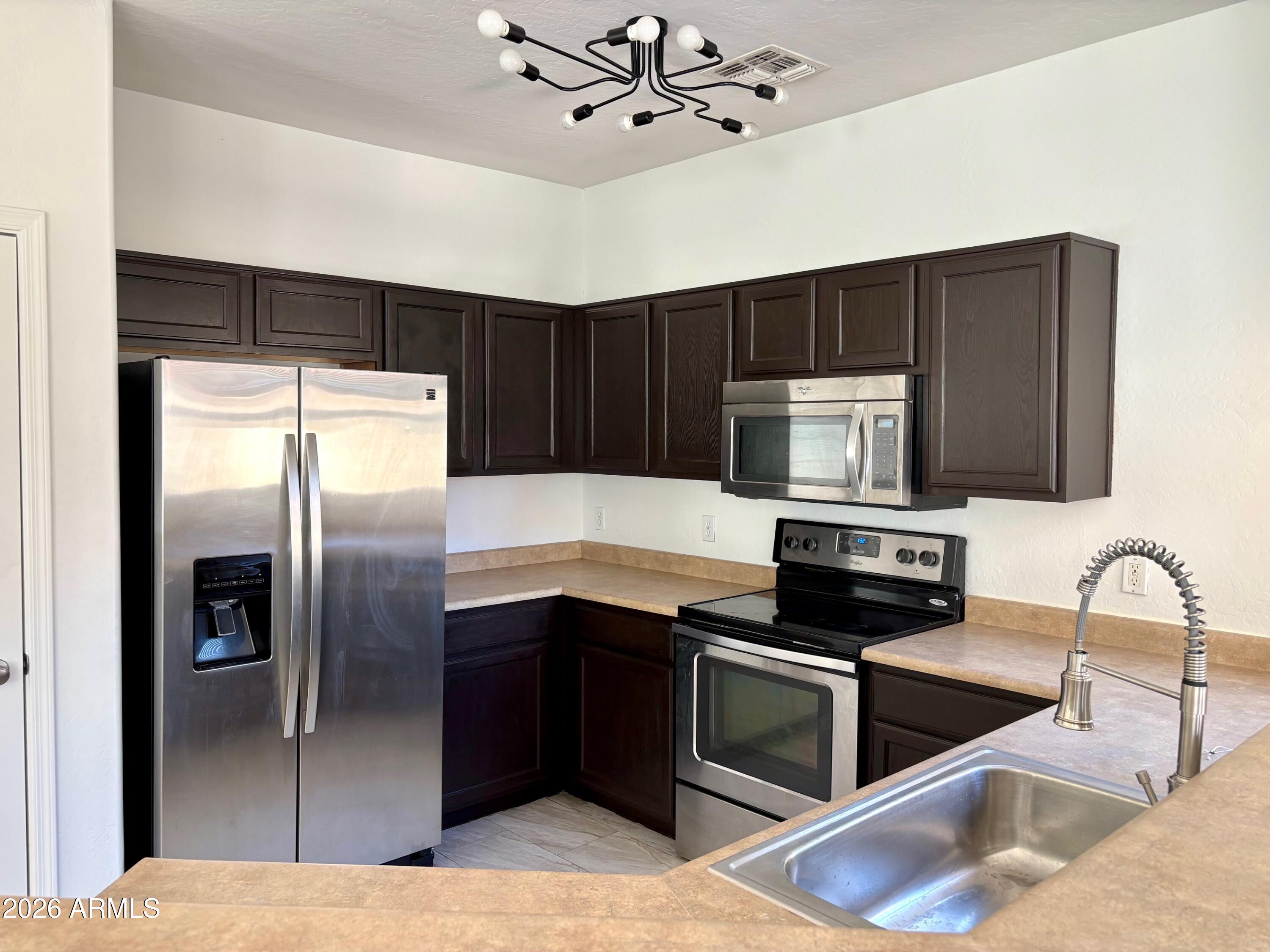 525 North Miller Road, Unit 239 Scottsdale, AZ 85257 - Photo 3 of 52 a kitchen with stainless steel appliances granite countertop a refrigerator a stove and a sink with wooden floor