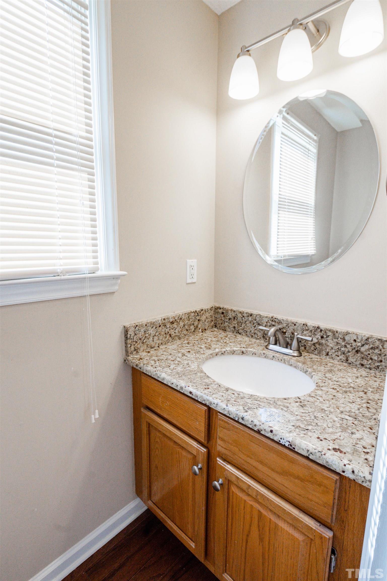99 Windsor Drive Angier, NC 27501 - Photo 18 of 21 a bathroom with a granite countertop sink a mirror and a window