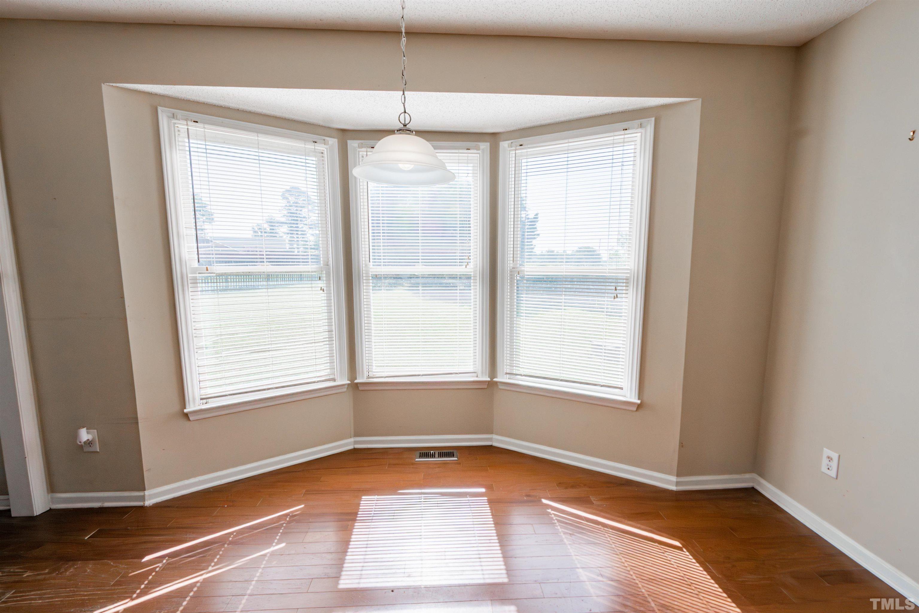 99 Windsor Drive Angier, NC 27501 - Photo 8 of 21 an empty room with wooden floor exposed radiator and windows