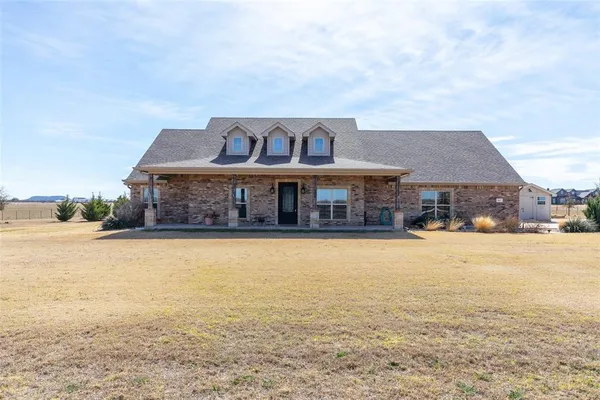 a front view of house with yard and ocean