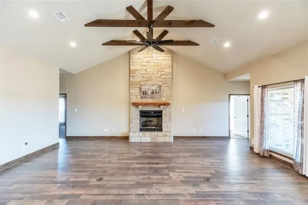 a view of a livingroom with a fireplace a ceiling fan and wooden floor