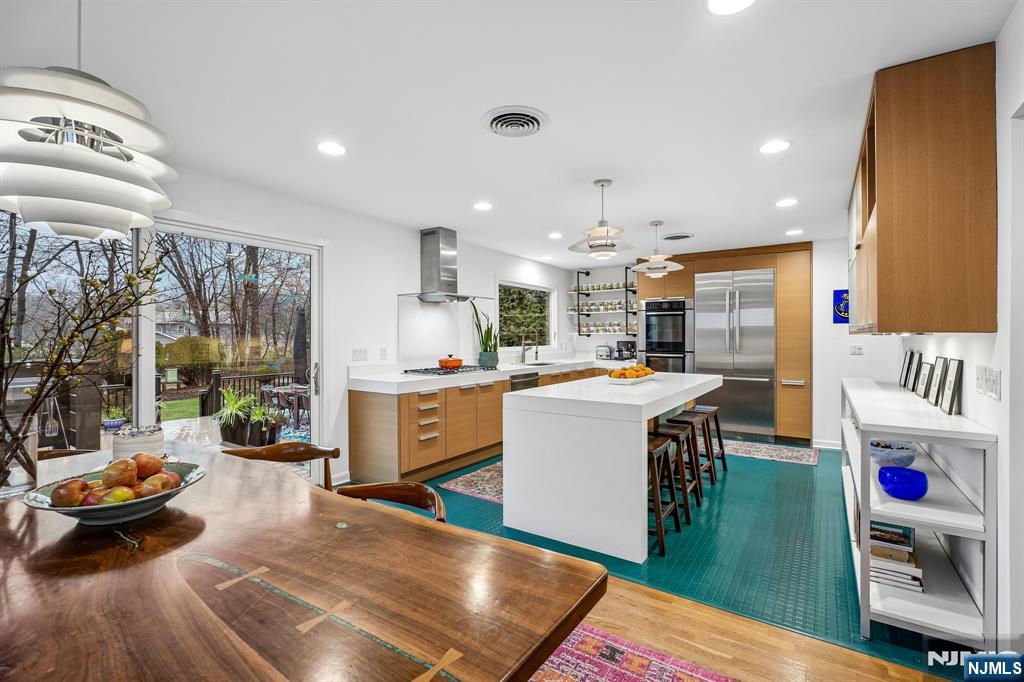 398 Grove Street Montclair, NJ 07043 - Photo 7 of 48 a kitchen with stainless steel appliances granite countertop a refrigerator a sink dishwasher a dining table and chairs with wooden floor