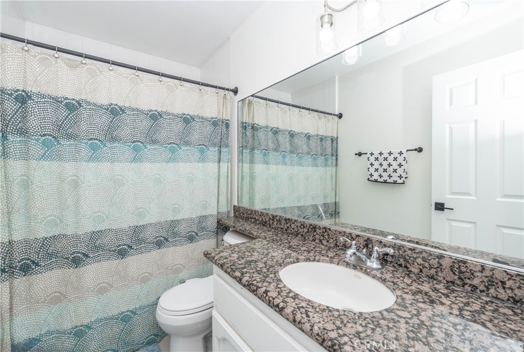 11520 Los Molinos Way Riverside, CA 92505 - Photo 15 of 26 a bathroom with a granite countertop sink a mirror and a toilet