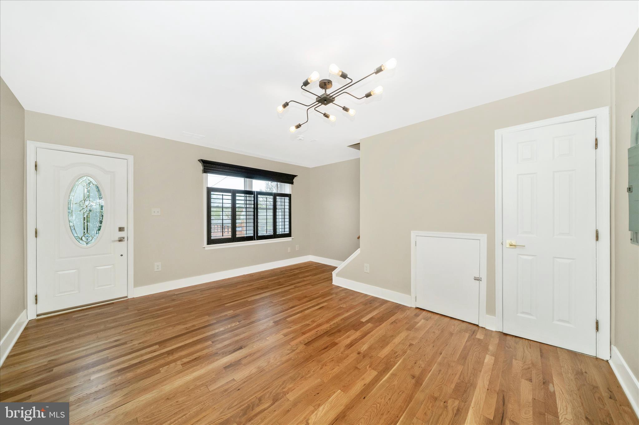 5045 Sheriff Road Northeast Washington, DC 20019 - Photo 3 of 38 an empty room with wooden floor chandelier fan and windows