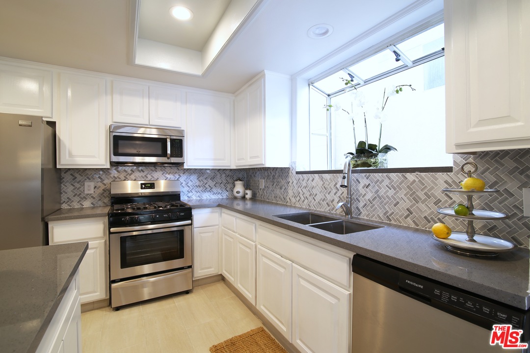 1811 Manning Avenue, Unit 202 Los Angeles, CA 90025 - Photo 9 of 18 a kitchen with granite countertop a sink stainless steel appliances and white cabinets