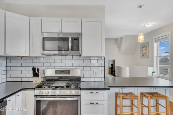 a kitchen with granite countertop stainless steel appliances a refrigerator and a stove top oven