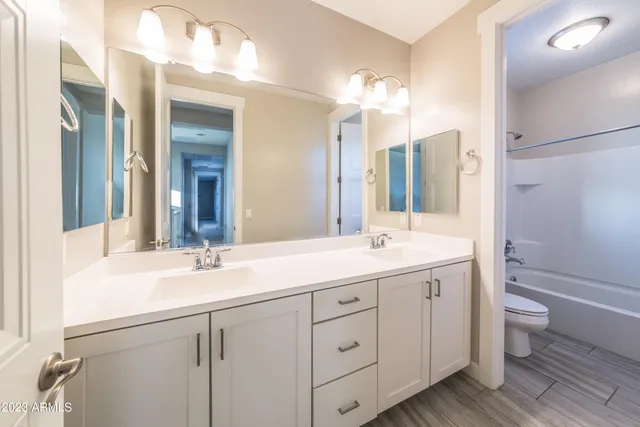 a bathroom with a double vanity sink a toilet and a mirror