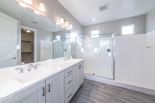 a bathroom with a double vanity sink mirror and shower