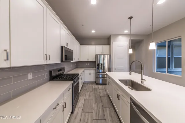a kitchen with a sink a counter top space stainless steel appliances and cabinets