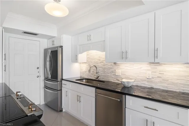 a kitchen with granite countertop a sink cabinets and stainless steel appliances