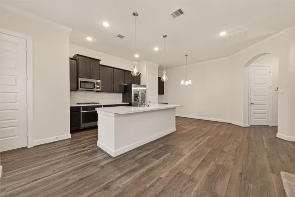 a large kitchen with stainless steel appliances a large counter top a stove and a refrigerator