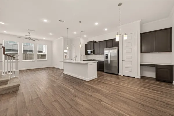 a large kitchen with kitchen island a island wooden floor stainless steel appliances and cabinets