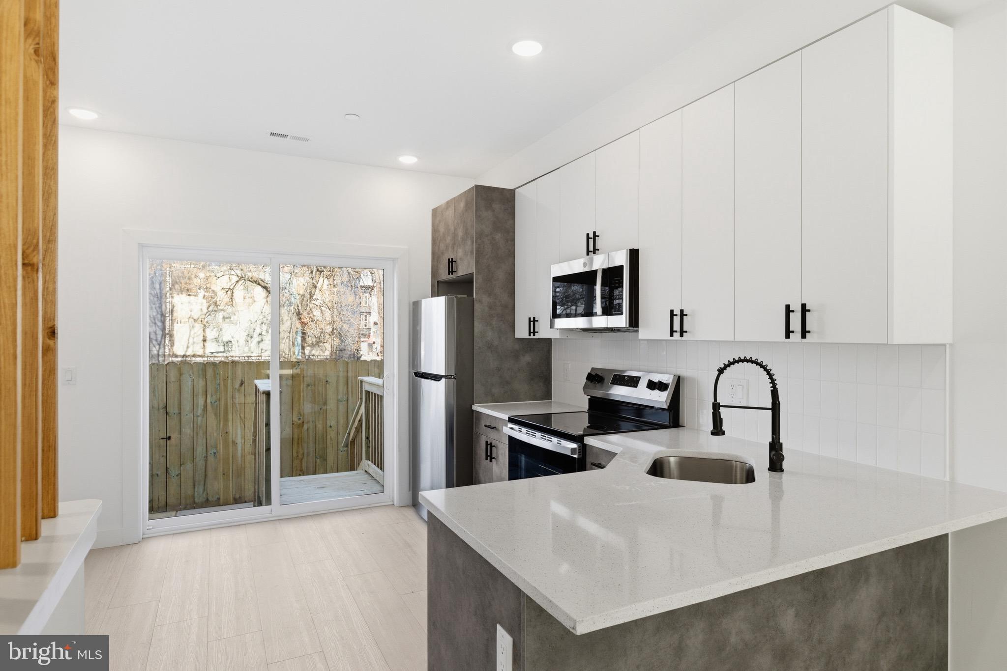 1005 West Orleans Street Philadelphia, PA 19133 - Photo 1 of 25 a kitchen with stainless steel appliances granite countertop a sink a stove and a refrigerator